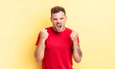 Genç, yakışıklı, İspanyol bir adam sinirli, sinirli, sinirli bakışlar ve sıkı yumruklar ile agresif bir şekilde bağırıyor.