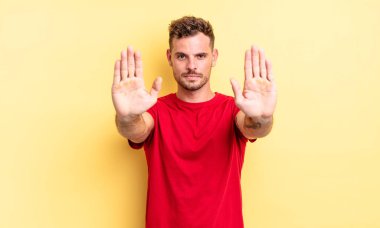 Genç, yakışıklı İspanyol adam ciddi, mutsuz, kızgın ve hoşnutsuz görünüyor. Girmeyi yasaklıyor ya da her iki avucunun içinde de dur diyor.