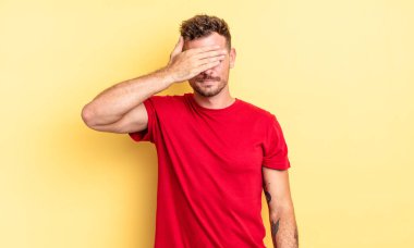 Genç, yakışıklı İspanyol bir adam tek eliyle gözlerini kapatıyor korkmuş ya da endişeli hissediyor, merak ediyor ya da körü körüne bir sürpriz bekliyor.