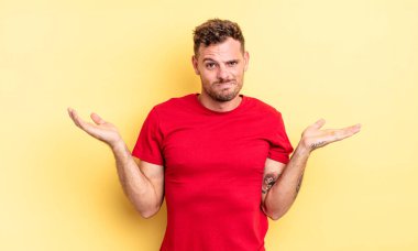 Genç, yakışıklı, şaşkın, kafası karışmış ve stresli görünen, farklı seçenekler arasında merak eden, belirsiz hisseden İspanyol bir adam.