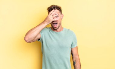 Genç, yakışıklı İspanyol bir adam şok olmuş, korkmuş ya da korkmuş görünüyor. Yüzü elle kaplanmış ve parmaklarının arasından gizlice bakıyor.