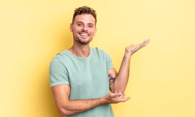 Genç, yakışıklı İspanyol adam gururla ve güvenle gülümsüyor, mutlu ve tatmin olmuş hissediyor ve fotokopi alanında bir konsept gösteriyor.