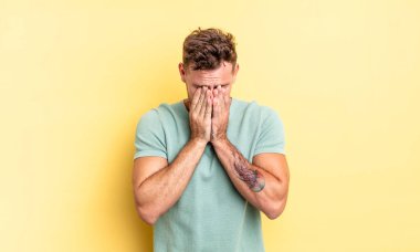 Genç, yakışıklı İspanyol adam üzgün, hayal kırıklığına uğramış, gergin ve depresif, iki eliyle yüzünü kaplayan, ağlayan