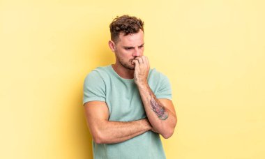 Genç, yakışıklı İspanyol bir adam ciddi, düşünceli ve endişeli hissediyor. Eli çenesine değmiş şekilde yan yan bakıyor.