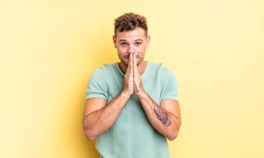 Genç, yakışıklı İspanyol adam endişeli, umut dolu ve dindar. Avuçlarına bastırılmış, af dilenen sadık bir şekilde dua ediyor.