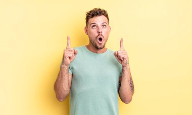 Genç, yakışıklı, İspanyol görünümlü, şaşkın ve ağzı açık, iki eliyle uzayı gösteren