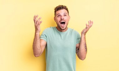 Genç, yakışıklı İspanyol adam kendini mutlu, şaşkın, şanslı ve şaşırmış hissediyor. Zaferi iki eli havada kutluyor.