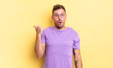 Genç, yakışıklı İspanyol adam, inançsızlıktan şaşkın şaşkın bakıyor, yan taraftaki objeyi işaret ediyor ve diyor ki: