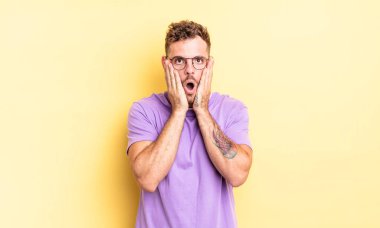 Genç, yakışıklı İspanyol adam şok olmuş ve korkmuş hissediyor, ağzı açık ve elleri yanaklarında korkmuş görünüyor.