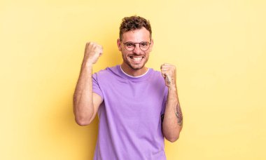 Genç, yakışıklı İspanyol adam mutlu, şaşırmış ve gururlu hissediyor, bağırıyor ve başarıyı büyük bir gülümsemeyle kutluyor.