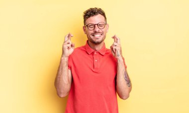 Genç, yakışıklı İspanyol adam gülümsüyor ve endişeyle iki parmağını çapraz yapıyor. Endişeli ve iyi şanslar diliyor.