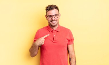 Genç yakışıklı İspanyol gururlu, kendinden emin ve mutlu görünüyor, gülümsüyor ve kendini işaret ediyor ya da bir numaralı işareti yapıyor.