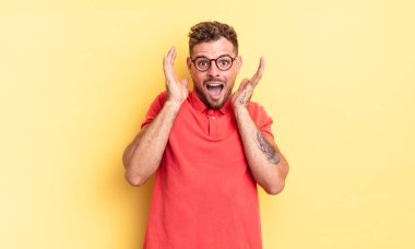 Genç, yakışıklı İspanyol bir adam beklenmedik bir sürpriz yüzünden şoke olmuş, heyecanlı, gülen, şaşkın ve mutlu hissediyor.