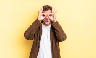 Genç, yakışıklı İspanyol bir adam şok olmuş, şaşırmış ve şaşırmış hissediyor. Elinde şaşkın, inançsız bir bakışla gözlük tutuyor.