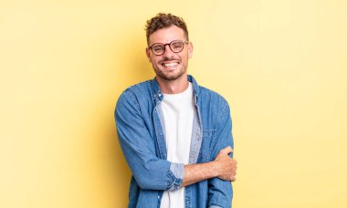 Genç, yakışıklı İspanyol adam utangaç ve neşeli bir şekilde gülüyor, arkadaş canlısı, olumlu ama güvensiz bir tavırla.