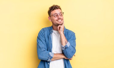 Genç, yakışıklı İspanyol adam mutlu bir şekilde gülümsüyor ve hayal kuruyor ya da şüphe ediyor.