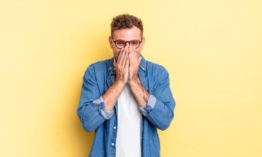 Genç yakışıklı İspanyol adam mutlu, neşeli, şanslı ve şaşkın görünüyor iki eliyle ağzını kapatıyor.