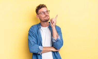 Genç yakışıklı İspanyol adam mutlu bir şekilde gülümsüyor ve yan bakıyor, merak ediyor, düşünüyor ya da bir fikri var.