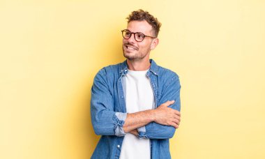 Genç, yakışıklı İspanyol adam kendini mutlu, gururlu ve umutlu hissediyor, merak ediyor ya da düşünüyor, çapraz kollarla fotokopi çekmeye çalışıyor.