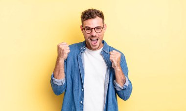 Genç, yakışıklı İspanyol adam şok olmuş, heyecanlı ve mutlu hissediyor, gülüyor ve başarıyı kutluyor,!