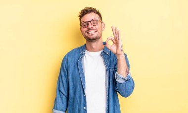 Genç, yakışıklı İspanyol adam mutlu, rahat ve tatmin olmuş hissediyor. Onayını iyi bir hareketle gösteriyor. Gülümsüyor.