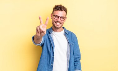 Genç, yakışıklı İspanyol adam gülümsüyor ve mutlu görünüyor, kaygısız ve pozitif, zafer ya da barışı simgeliyor.