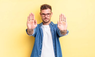 Genç, yakışıklı İspanyol adam ciddi, mutsuz, kızgın ve hoşnutsuz görünüyor. Girmeyi yasaklıyor ya da her iki avucunun içinde de dur diyor.