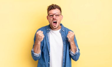 Genç, yakışıklı, İspanyol bir adam sinirli, sinirli, sinirli bakışlar ve sıkı yumruklar ile agresif bir şekilde bağırıyor.