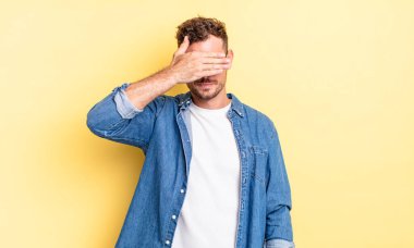 Genç, yakışıklı İspanyol bir adam tek eliyle gözlerini kapatıyor korkmuş ya da endişeli hissediyor, merak ediyor ya da körü körüne bir sürpriz bekliyor.