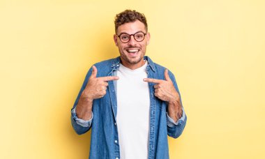 Genç, yakışıklı İspanyol adam mutlu, şaşkın ve gururlu hissediyor. Heyecanlı ve şaşkın bir bakışla kendini işaret ediyor.