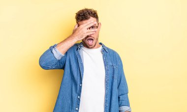 Genç, yakışıklı İspanyol bir adam şok olmuş, korkmuş ya da korkmuş görünüyor. Yüzü elle kaplanmış ve parmaklarının arasından gizlice bakıyor.