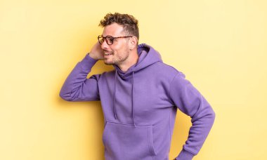 Genç, yakışıklı İspanyol bir adam gülümsüyor, tuhaf bir şekilde yan tarafa bakıyor, bir dedikoduyu dinlemeye ya da bir sırrı duymaya çalışıyor.