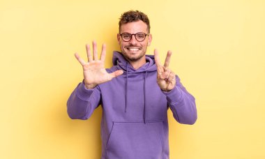 Genç, yakışıklı İspanyol adam gülümsüyor ve dost canlısı görünüyor. Elleri önde, geriye doğru sayarak yedi ya da yedi numarayı gösteriyor.