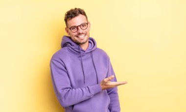 Genç, yakışıklı İspanyol adam neşeyle gülümsüyor, mutlu hissediyor ve fotokopi uzayda bir kavram gösteriyor.