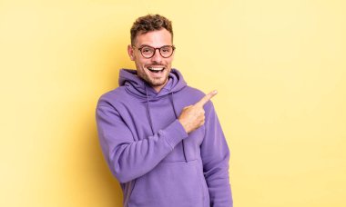 Genç, yakışıklı İspanyol adam heyecanlı ve şaşırmış görünüyor. Yana ve yukarıya bakıp boşluğu kopyalıyor.