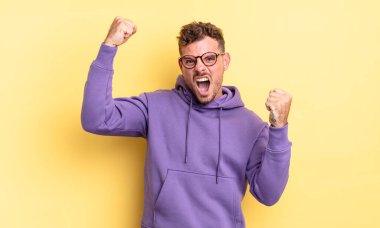 Genç, yakışıklı İspanyol adam zaferle bağırıyor. Heyecanlı, mutlu ve şaşırmış görünüyor. Kutlama yapıyor.