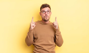 Genç, yakışıklı İspanyol bir adam korkuyla ve ağzı açık bir şekilde şaşkın ve şaşkın bir bakışla yukarı bakıyor.