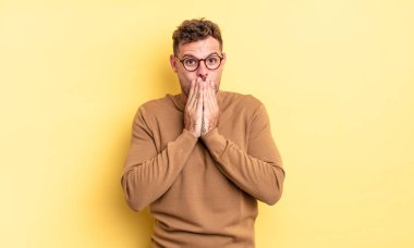 Genç, yakışıklı İspanyol adam mutlu ve heyecanlı, şaşırmış ve hayrete düşmüş elleriyle ağzını kapatmış, tatlı bir ifadeyle kıkırıyor.