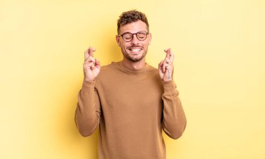 Genç, yakışıklı İspanyol adam gülümsüyor ve endişeyle iki parmağını çapraz yapıyor. Endişeli ve iyi şanslar diliyor.