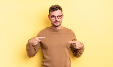 Genç, yakışıklı İspanyol bir adam gururlu, pozitif ve iki eliyle göğsünü gösteren