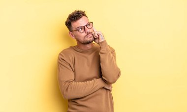 Dikkatle bakan, şüpheli bir ifadeyle, yukarı ve yana bakan, genç, yakışıklı İspanyol bir adam.