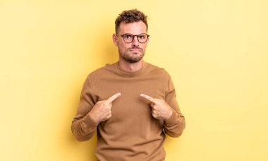 Genç, yakışıklı İspanyol bir adam, şaşkın ve şaşkın bir bakışla kendini işaret ediyor. Seçildiğime şaşırmış ve şaşırmış.