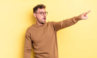 Genç, yakışıklı İspanyol bir adam şok olmuş ve şaşırmış hissediyor. Şaşkın ve açık ağızlı bir bakışla yukarılara bakıyor ve işaret ediyor.