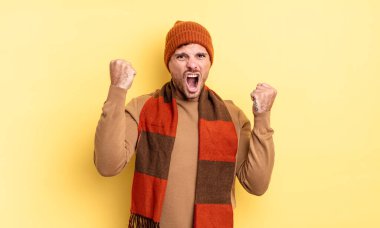 Genç, yakışıklı İspanyol bir adam öfkeli bir ifadeyle agresif bir şekilde bağırıyor ya da yumruklarıyla başarıyı kutluyor.