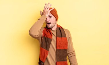 young handsome hispanic man raising palm to forehead thinking oops, after making a stupid mistake or remembering, feeling dumb