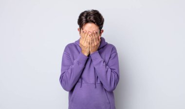 Genç, yakışıklı İspanyol adam üzgün, hayal kırıklığına uğramış, gergin ve depresif, iki eliyle yüzünü kaplayan, ağlayan