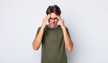 Genç, yakışıklı, İspanyol bir adam stresli ve hayal kırıklığına uğramış görünüyor. Baskı altında, baş ağrısı ve sorunlarıyla çalışıyor.