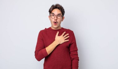 Genç, yakışıklı İspanyol bir adam şok olmuş ve şaşırmış hissediyor, gülümsüyor, el ele tutuşuyor, mutlu ya da şükran duyuyor.