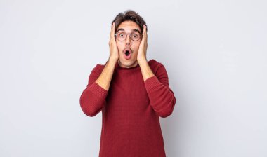 Genç, yakışıklı, İspanyol görünümlü, hoş olmayan, korkmuş ya da endişeli, ağzı açık ve iki kulağını da elleriyle kapatan bir adam.