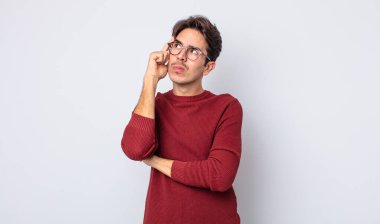 Dikkatle bakan, şüpheli bir ifadeyle, yukarı ve yana bakan, genç, yakışıklı İspanyol bir adam.